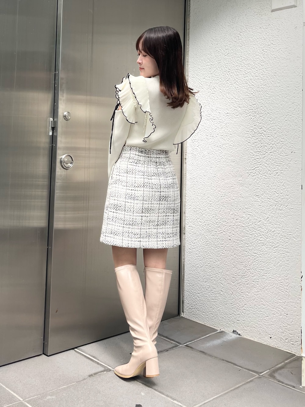 ホワイト系のニット/セーター、ホワイト系のスカート、ベージュ系のブーツを着用したレディースの秋コーディネートの3枚目の写真