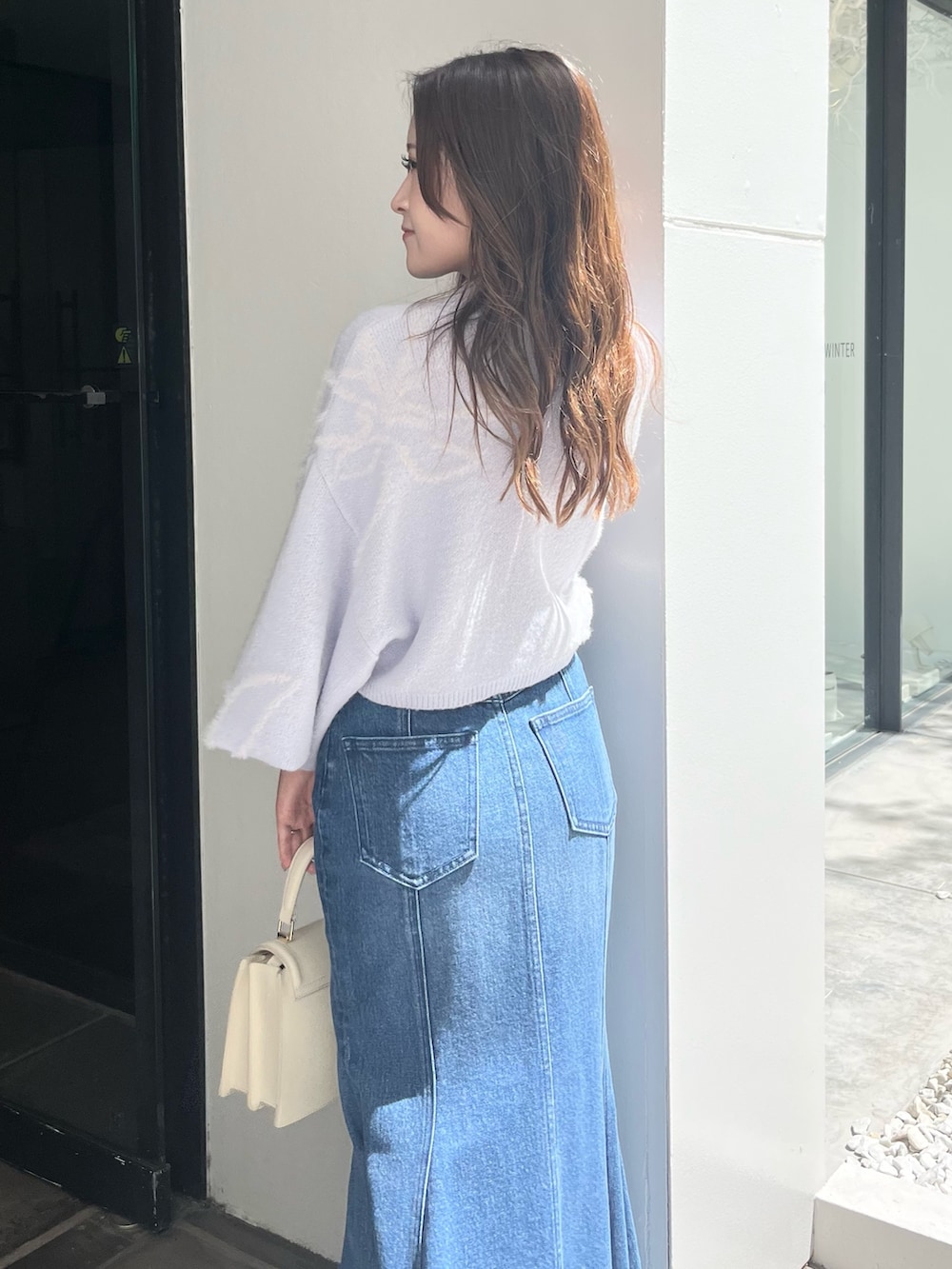 ブルー系のニット/セーター、ブルー系のデニムスカート、ベージュ系のブーツを着用したレディースの秋コーディネートの7枚目の写真