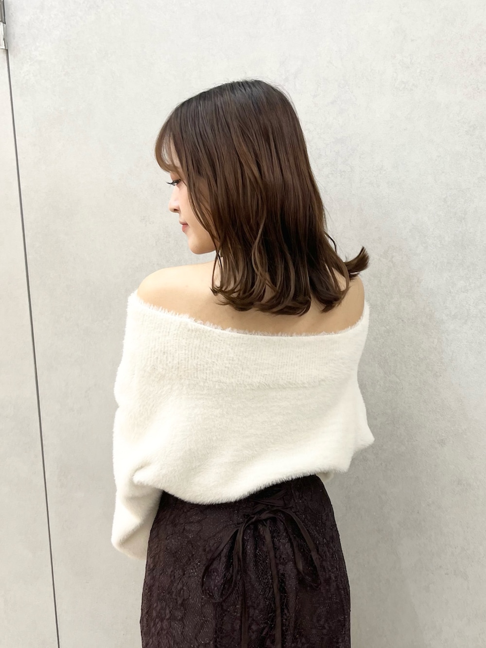 ホワイト系のニット/セーター、ブラウン系のスカート、ブラック系のブーツを着用したレディースの秋コーディネートの7枚目の写真