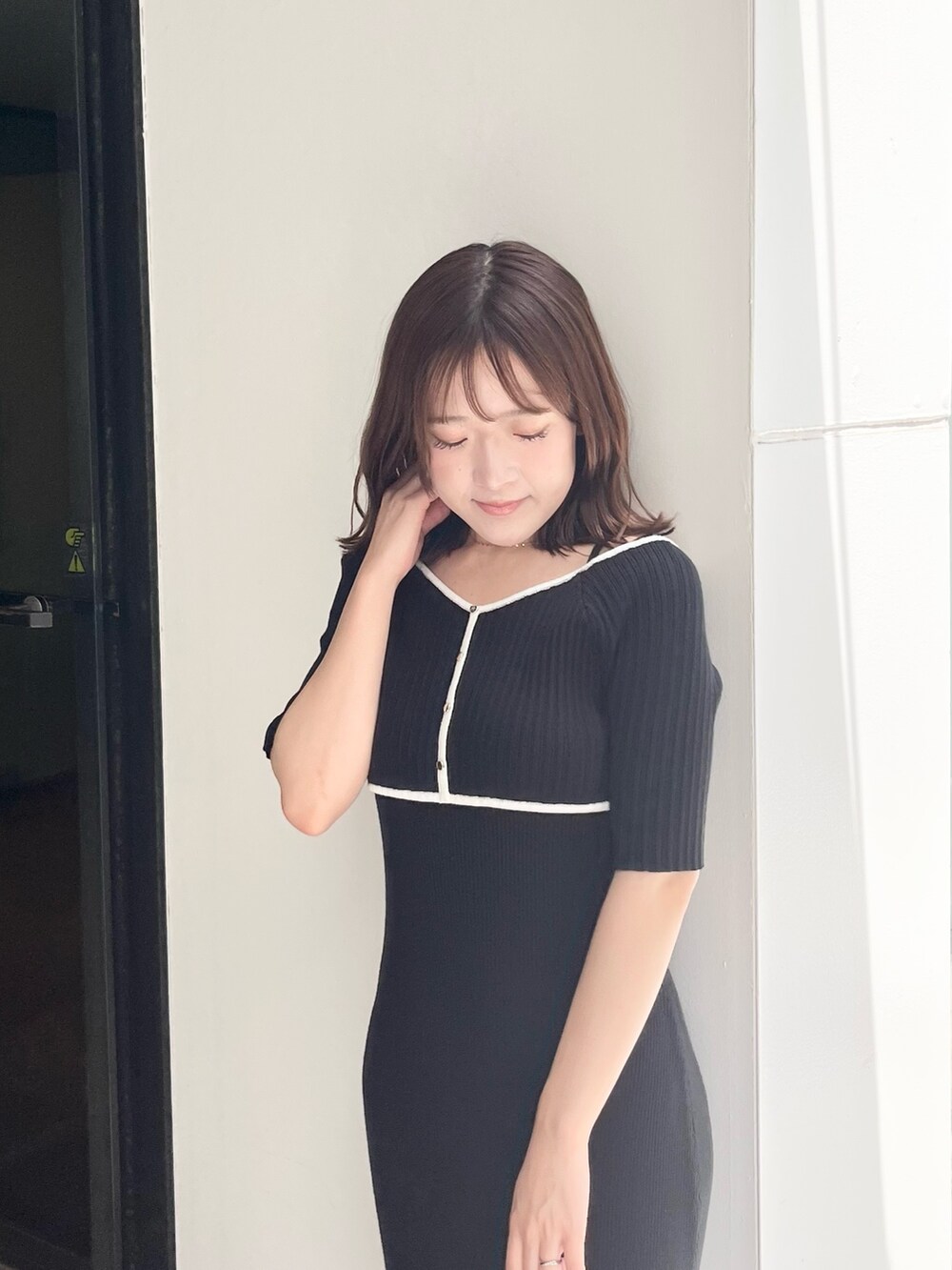 ブラック系のワンピース、ゴールド系のハンドバッグ、ホワイト系のブーツを着用したレディースの夏コーディネートの4枚目の写真