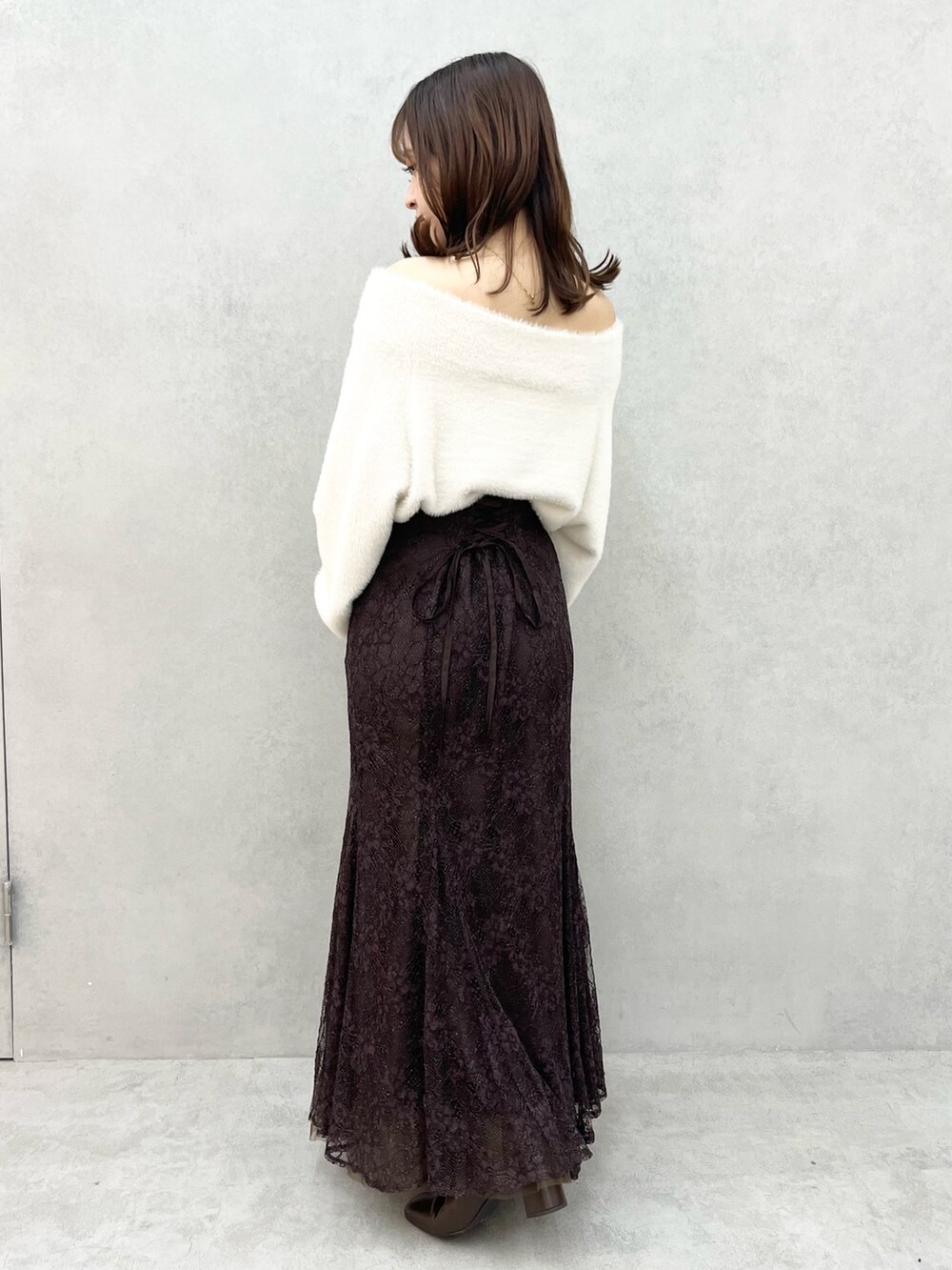 ホワイト系のニット/セーター、ブラウン系のスカート、ブラック系のブーツを着用したレディースの秋コーディネートの3枚目の写真