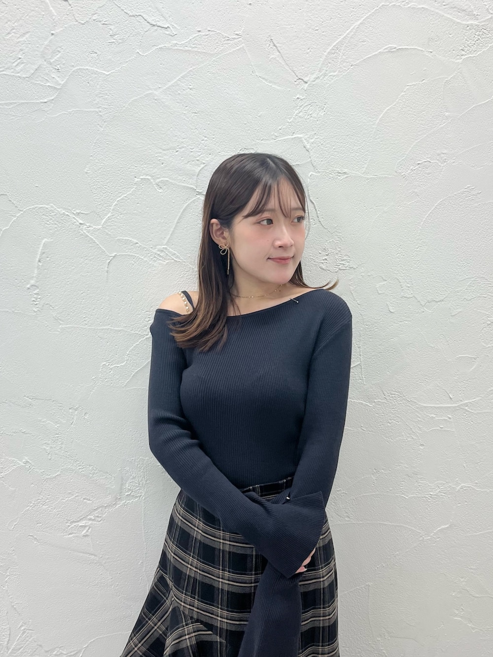 グレー系のニット/セーター、グレー系のスカート、ブラウン系のブーツを着用したレディースの秋コーディネートの3枚目の写真