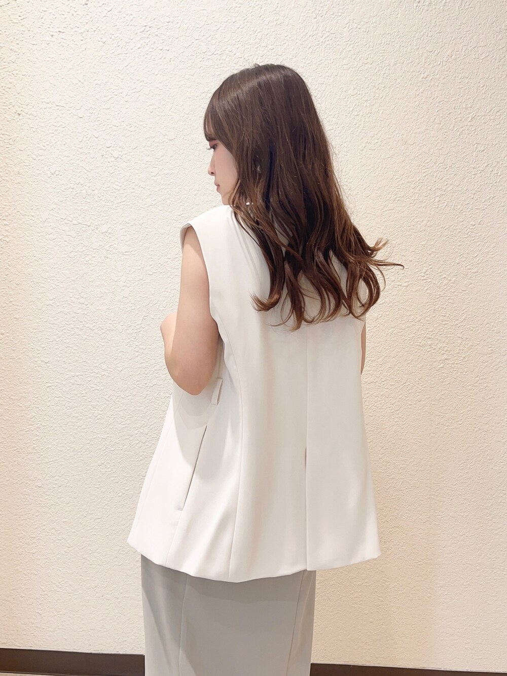 グリーン系のワンピース、ホワイト系のベスト、ブラック系のハンドバッグを着用したレディースの春コーディネートの4枚目の写真