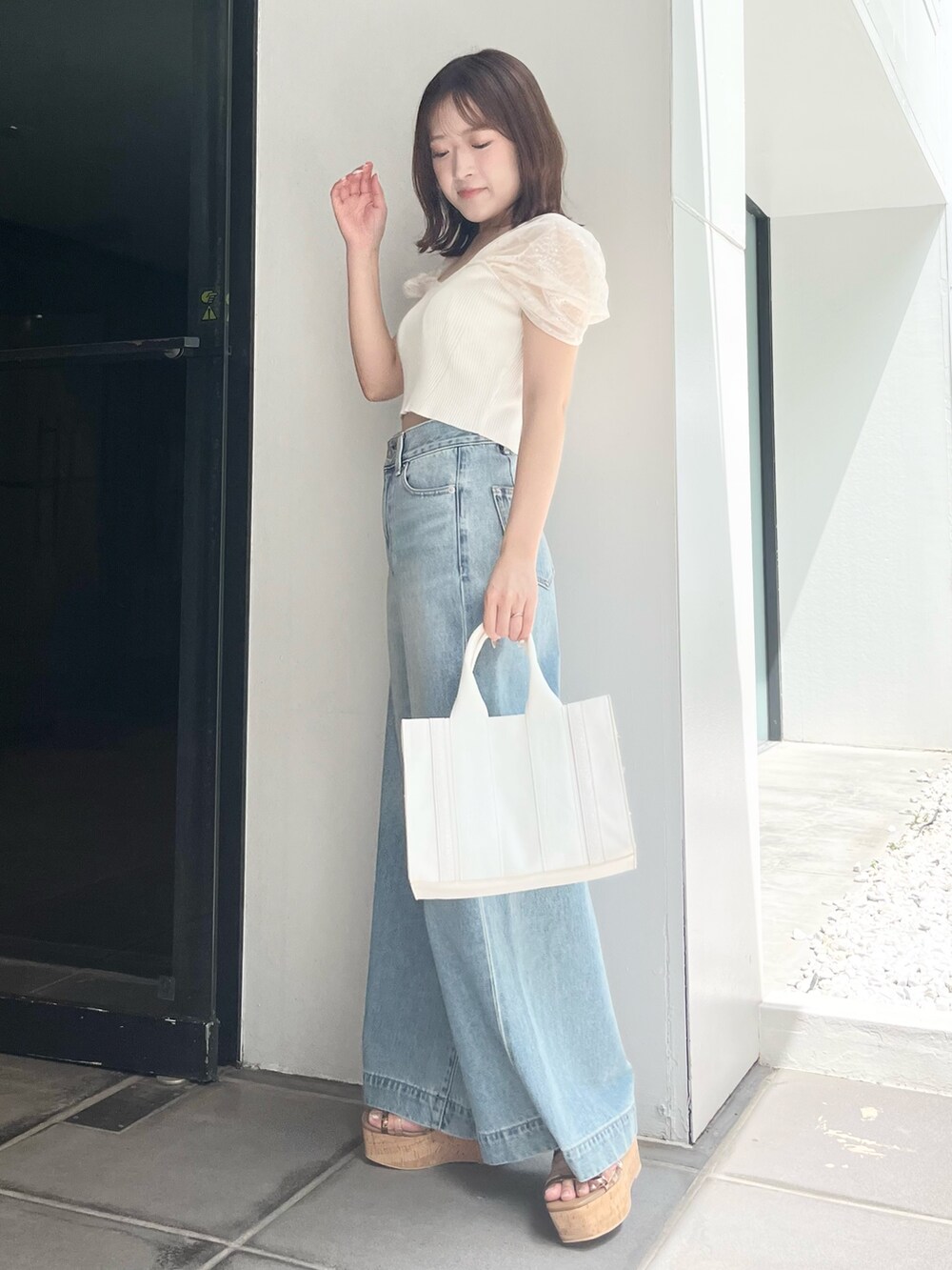 ホワイト系のニット/セーター、ブルー系のデニムパンツ、ホワイト系のトートバッグを着用したレディースの夏コーディネートの3枚目の写真