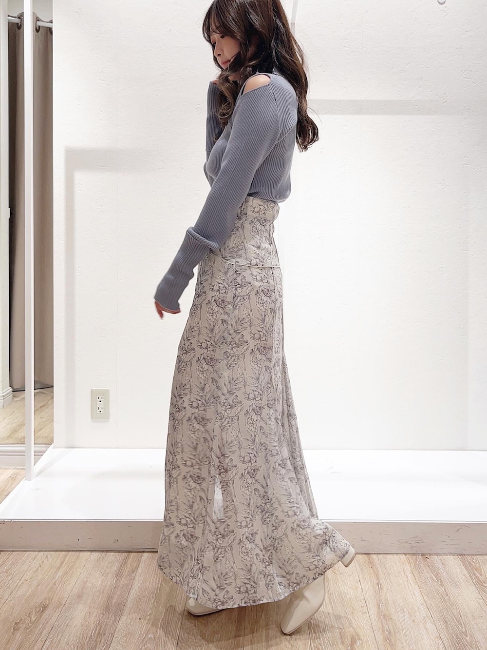 ホワイト系のスカート、ブルー系のニット/セーター、ホワイト系のブーツを着用したレディースの秋コーディネートの2枚目の写真