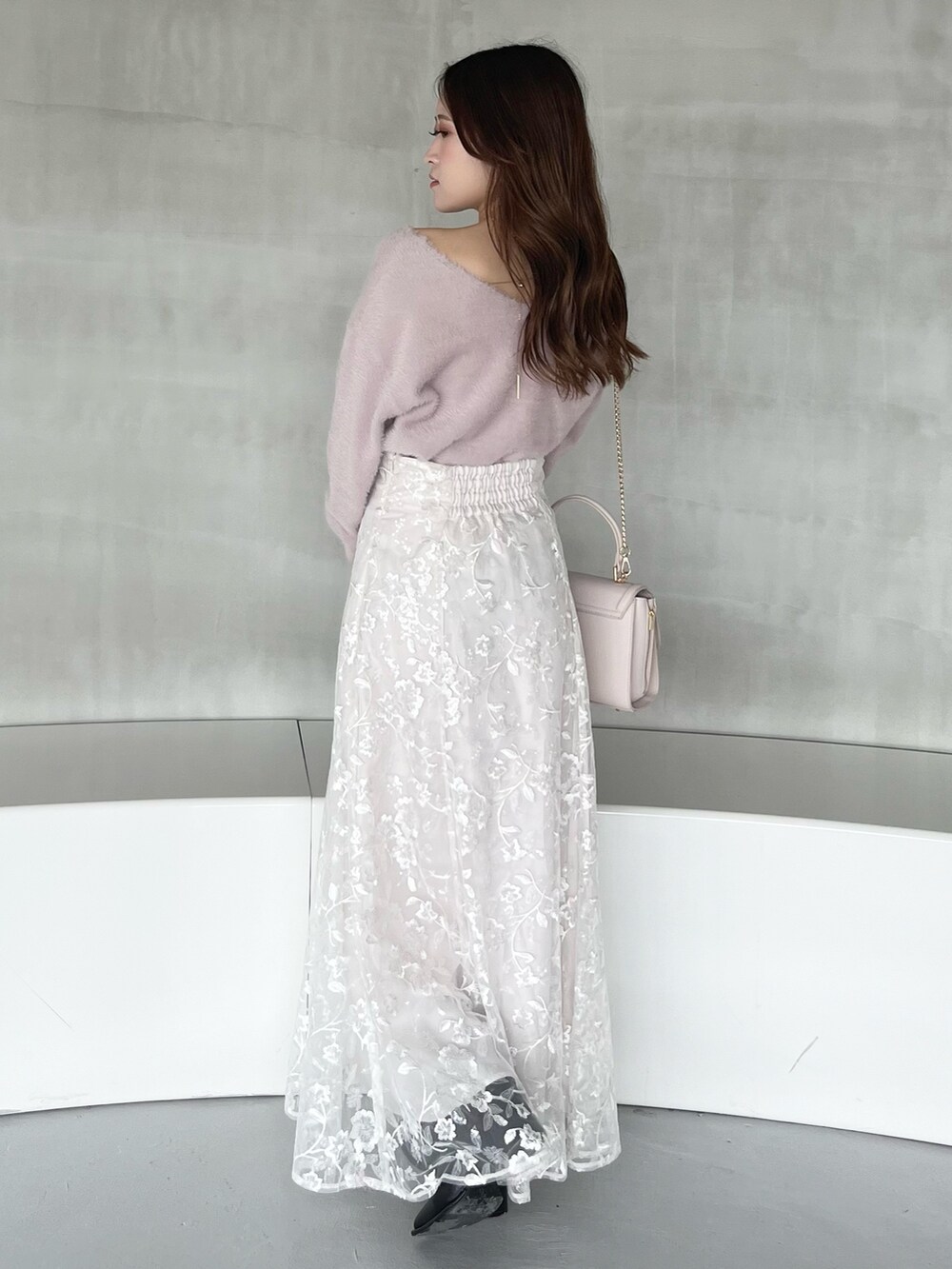 ホワイト系のスカート、ピンク系のニット/セーター、ピンク系のショルダーバッグを着用したレディースの秋コーディネートの3枚目の写真