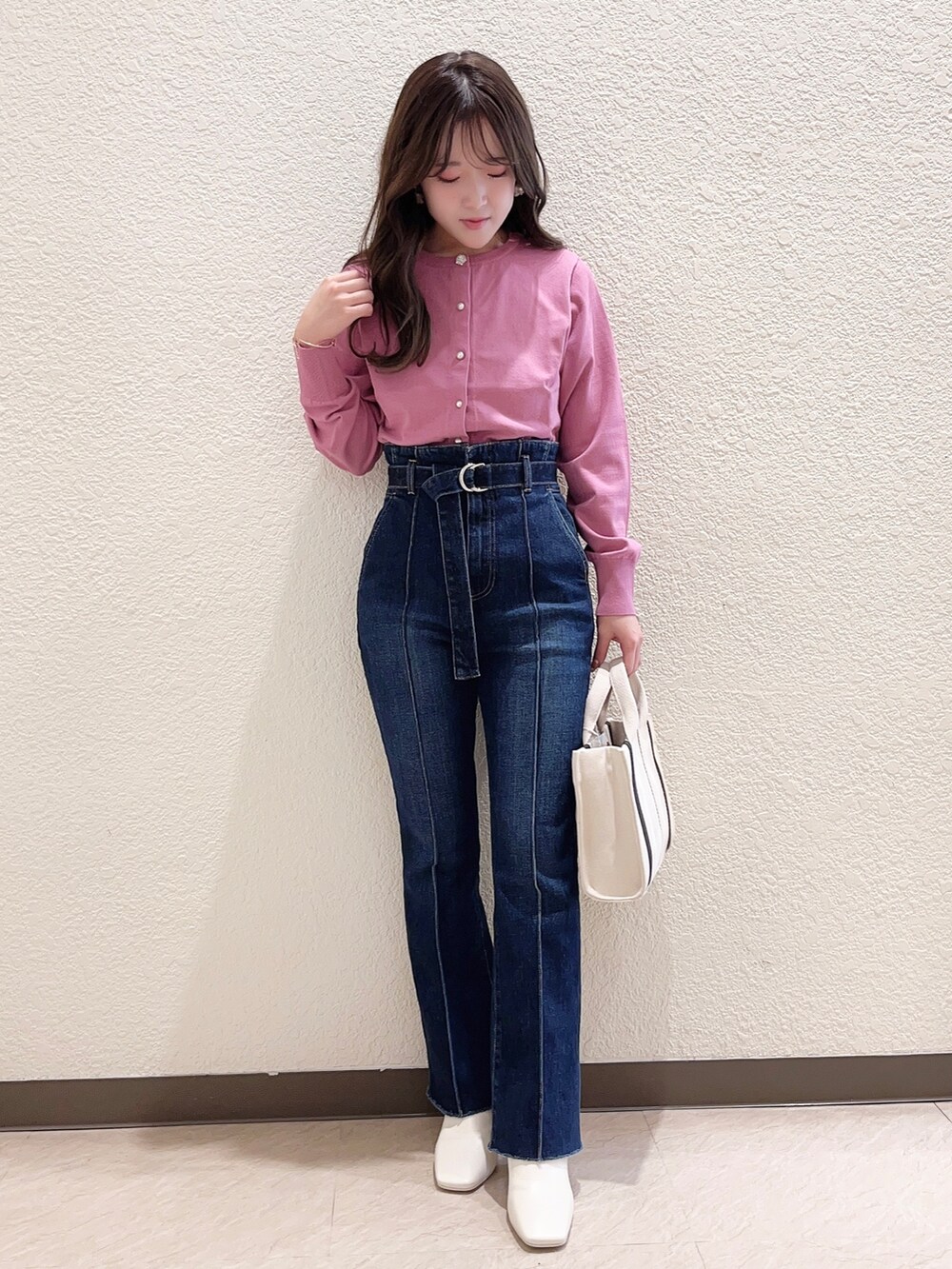 ピンク系のカーディガン/ボレロ、ブルー系のデニムパンツ、ホワイト系のハンドバッグを着用したレディースの冬コーディネートの2枚目の写真