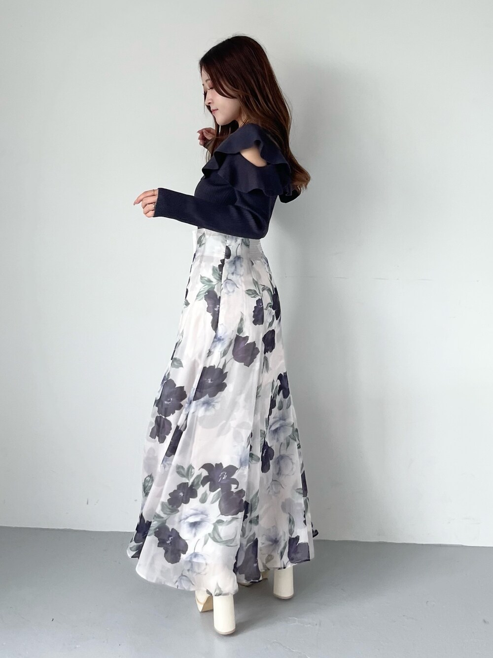 ブルー系のスカート、グレー系のニット/セーター、ホワイト系のブーツを着用したレディースの秋コーディネートの3枚目の写真