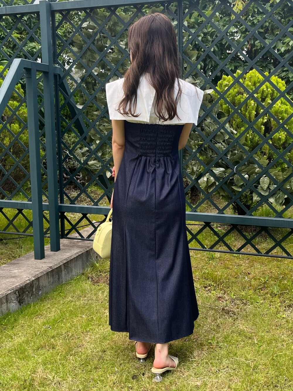 ブルー系のワンピース、イエロー系のボストンバッグ、イエロー系のサンダルを着用したレディースの夏コーディネートの3枚目の写真