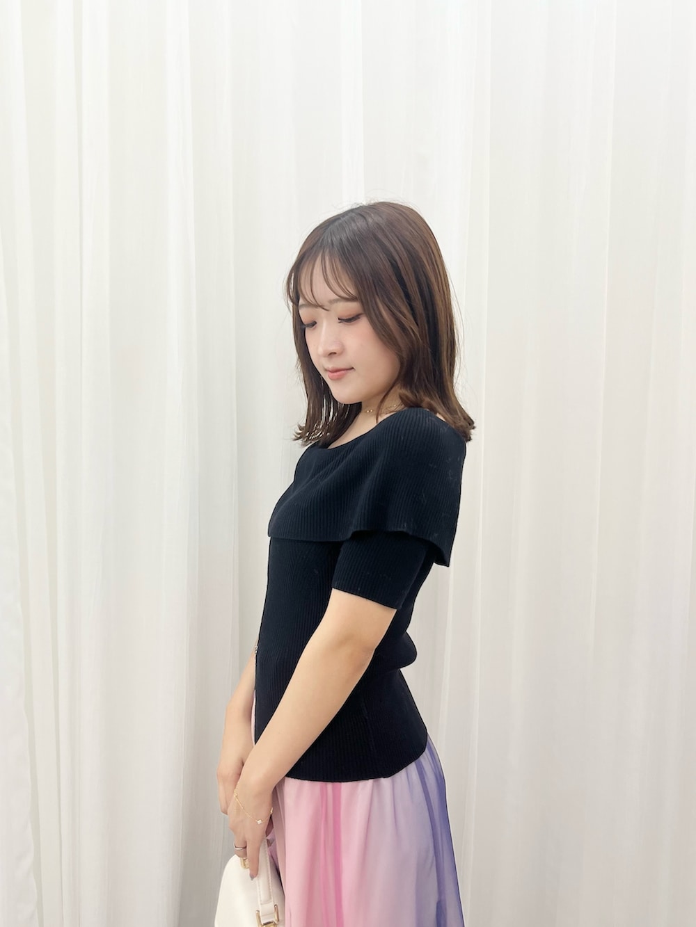 ブラック系のニット/セーター、パープル系のスカート、ベージュ系のパンプスを着用したレディースの夏コーディネートの4枚目の写真