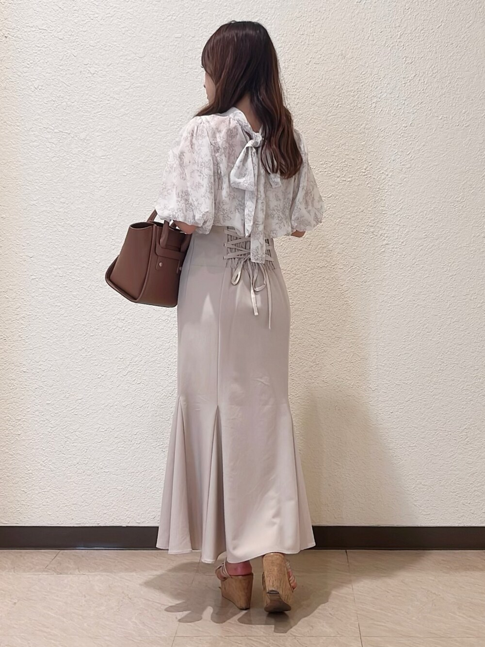 ベージュ系のシャツ/ブラウス、ベージュ系のスカート、ブラウン系のトートバッグを着用したレディースの春コーディネートの3枚目の写真