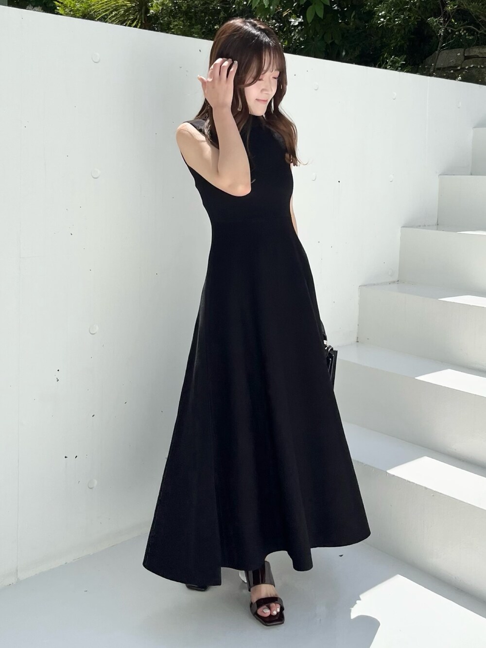 ブラック系のワンピース、ブラウン系のサンダル、ブラック系のハンドバッグを着用したレディースの春コーディネートの7枚目の写真