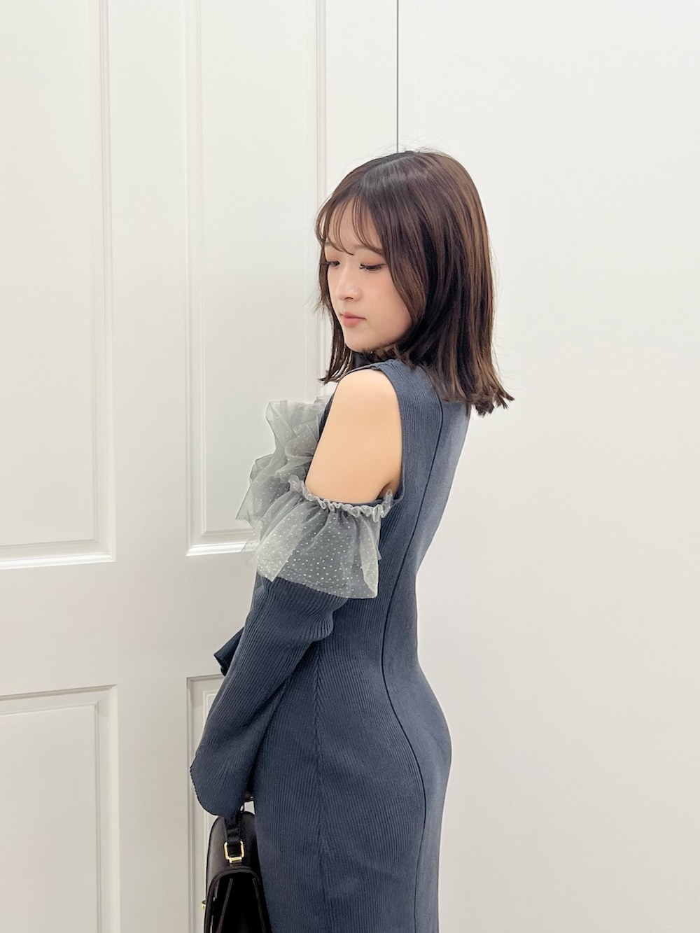 グレー系のワンピース、ブラウン系のハンドバッグ、ブラック系のブーツを着用したレディースの秋コーディネートの5枚目の写真