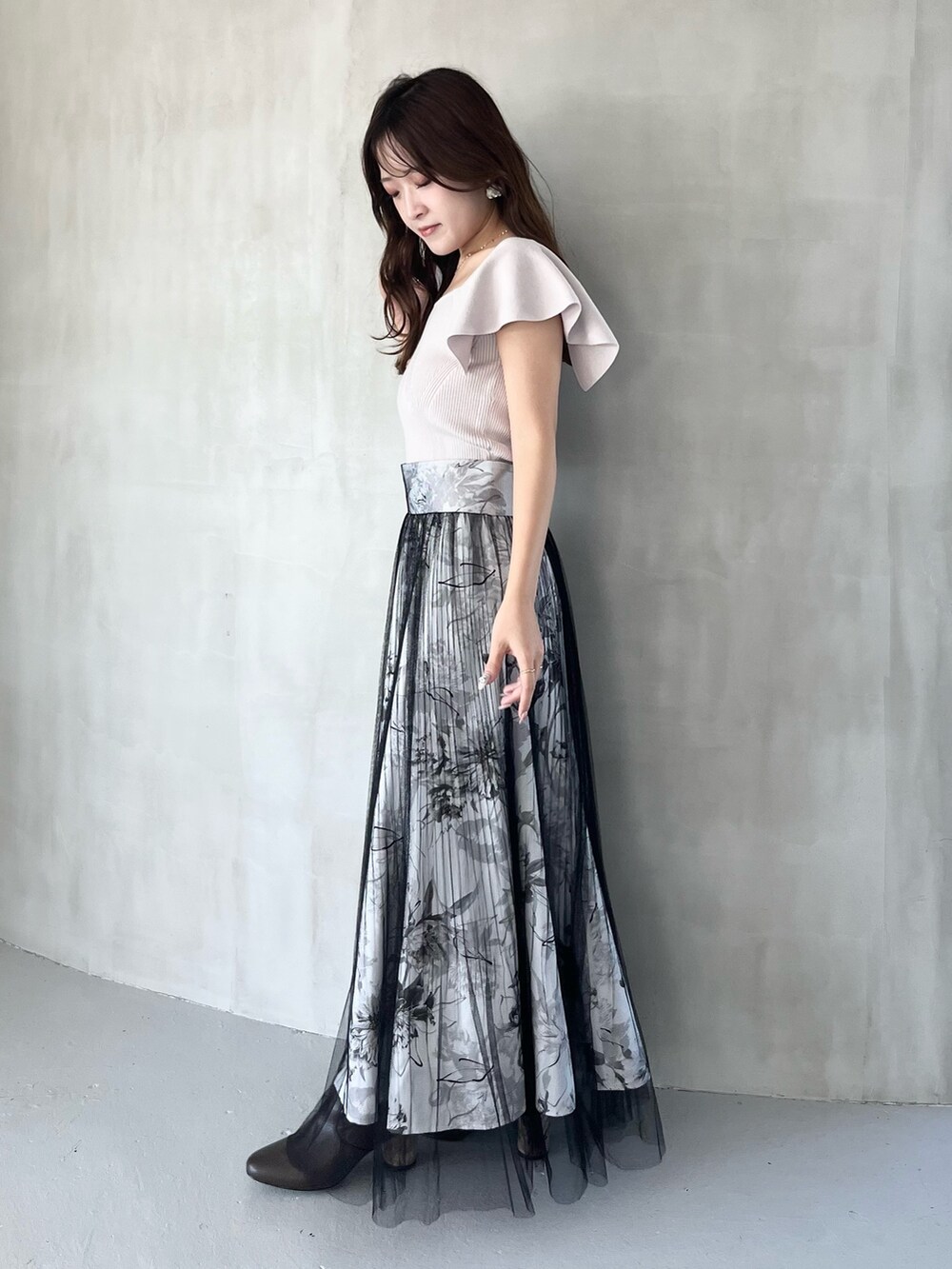 ブラック系のスカート、ピンク系のニット/セーター、ブラウン系のブーツを着用したレディースの春コーディネートの2枚目の写真