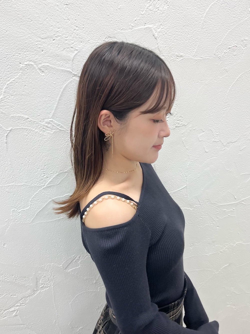 グレー系のニット/セーター、グレー系のスカート、ブラウン系のブーツを着用したレディースの秋コーディネートの5枚目の写真