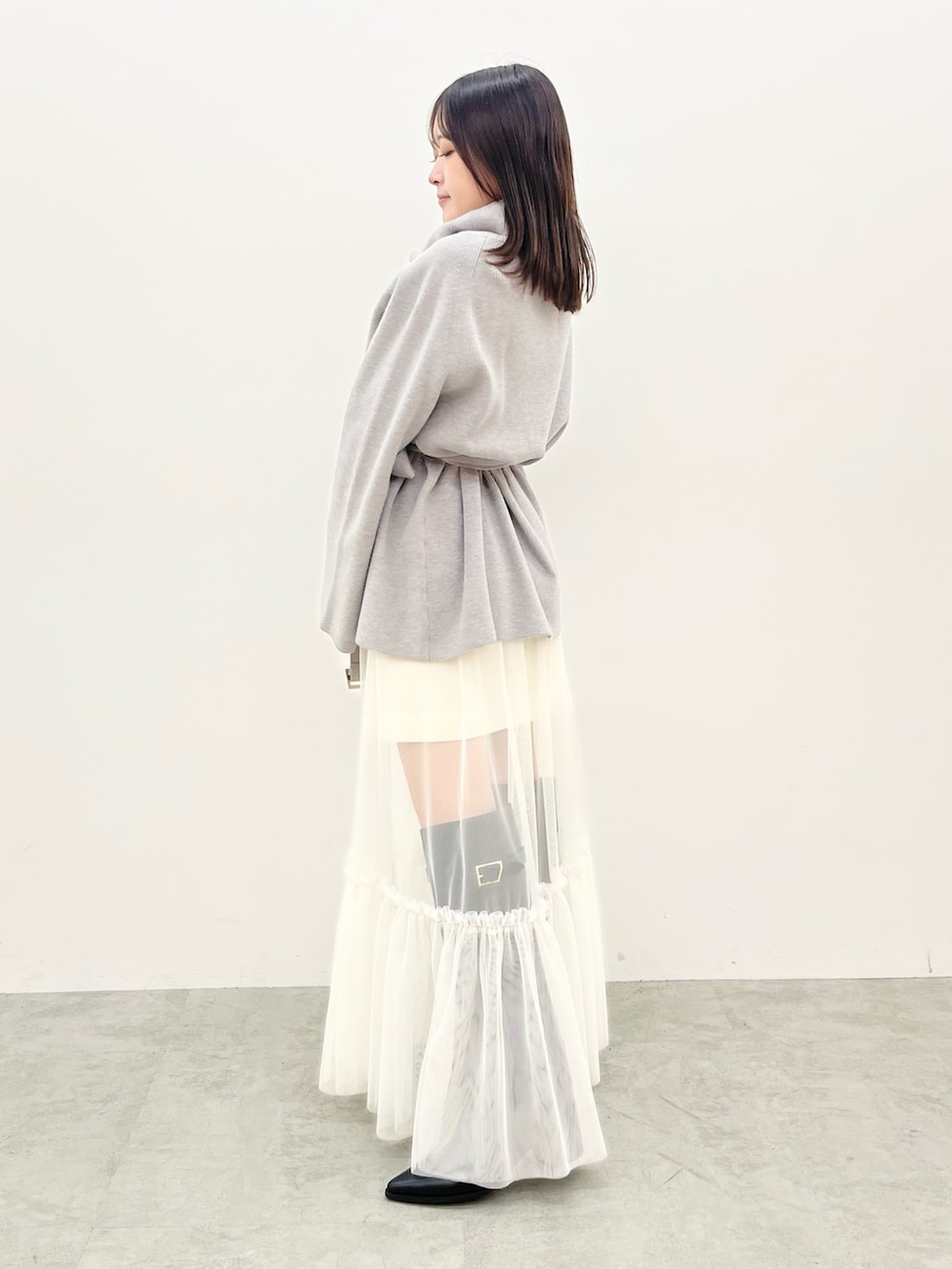 グレー系のニット/セーター、ホワイト系のスカートを着用したレディースの夏コーディネートの2枚目の写真