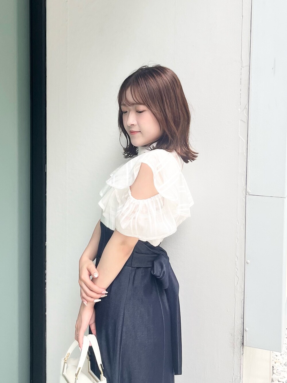 ホワイト系のワンピース、ホワイト系のハンドバッグ、ブラウン系のサンダルを着用したレディースの夏コーディネートの7枚目の写真