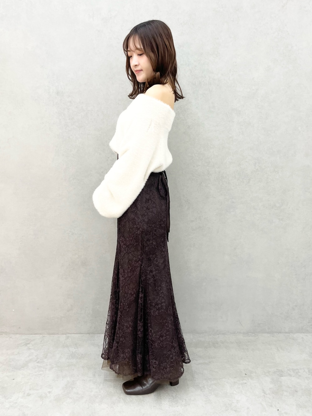 ホワイト系のニット/セーター、ブラウン系のスカート、ブラック系のブーツを着用したレディースの秋コーディネートの2枚目の写真