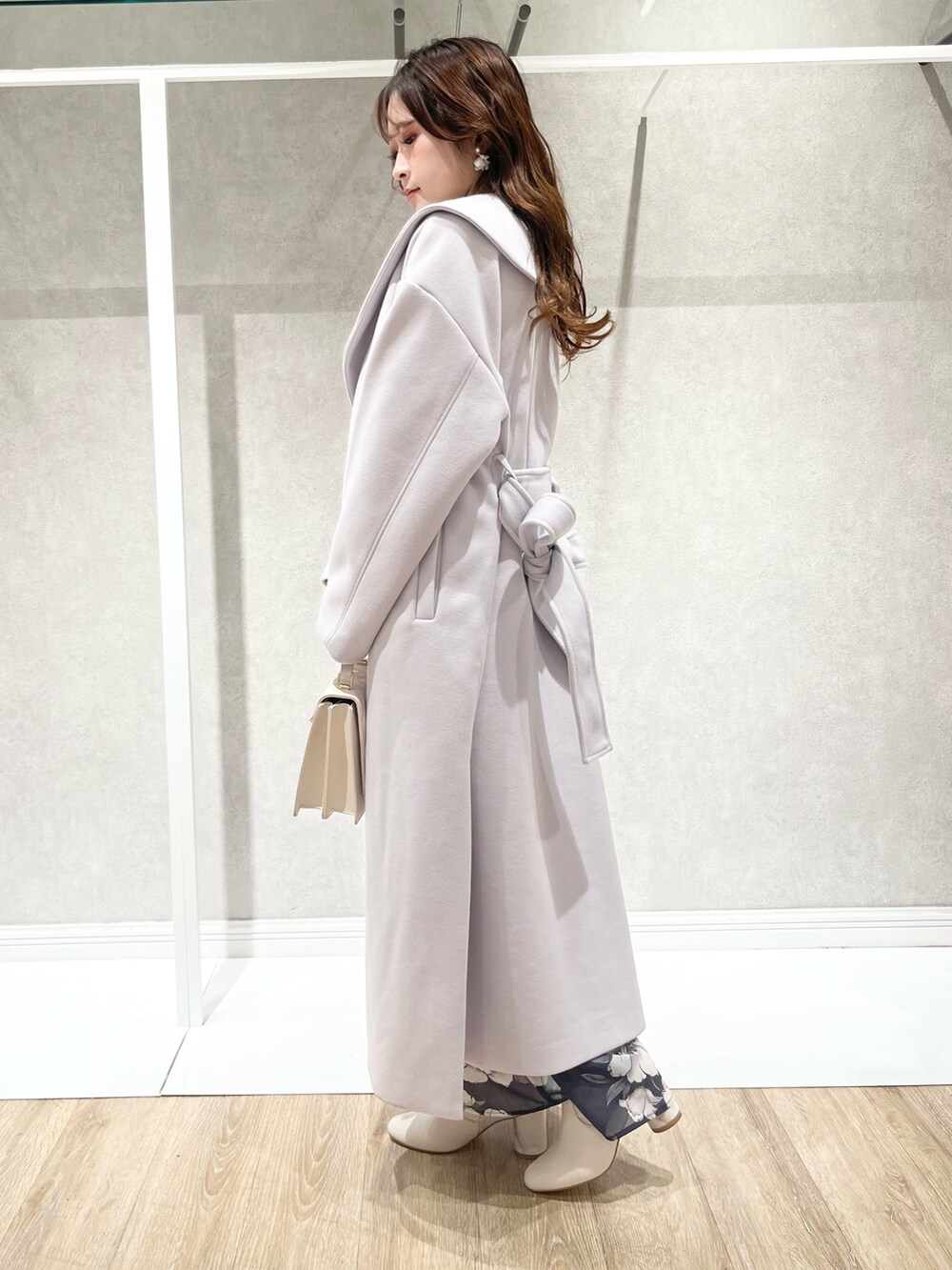 パープル系のチェスターコート、グレー系のワンピース、ホワイト系のショルダーバッグを着用したレディースの秋コーディネートの3枚目の写真