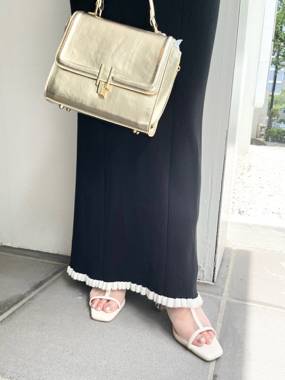 ブラック系のワンピース、ゴールド系のハンドバッグ、ホワイト系のブーツを着用したレディースの夏コーディネートの7枚目の写真