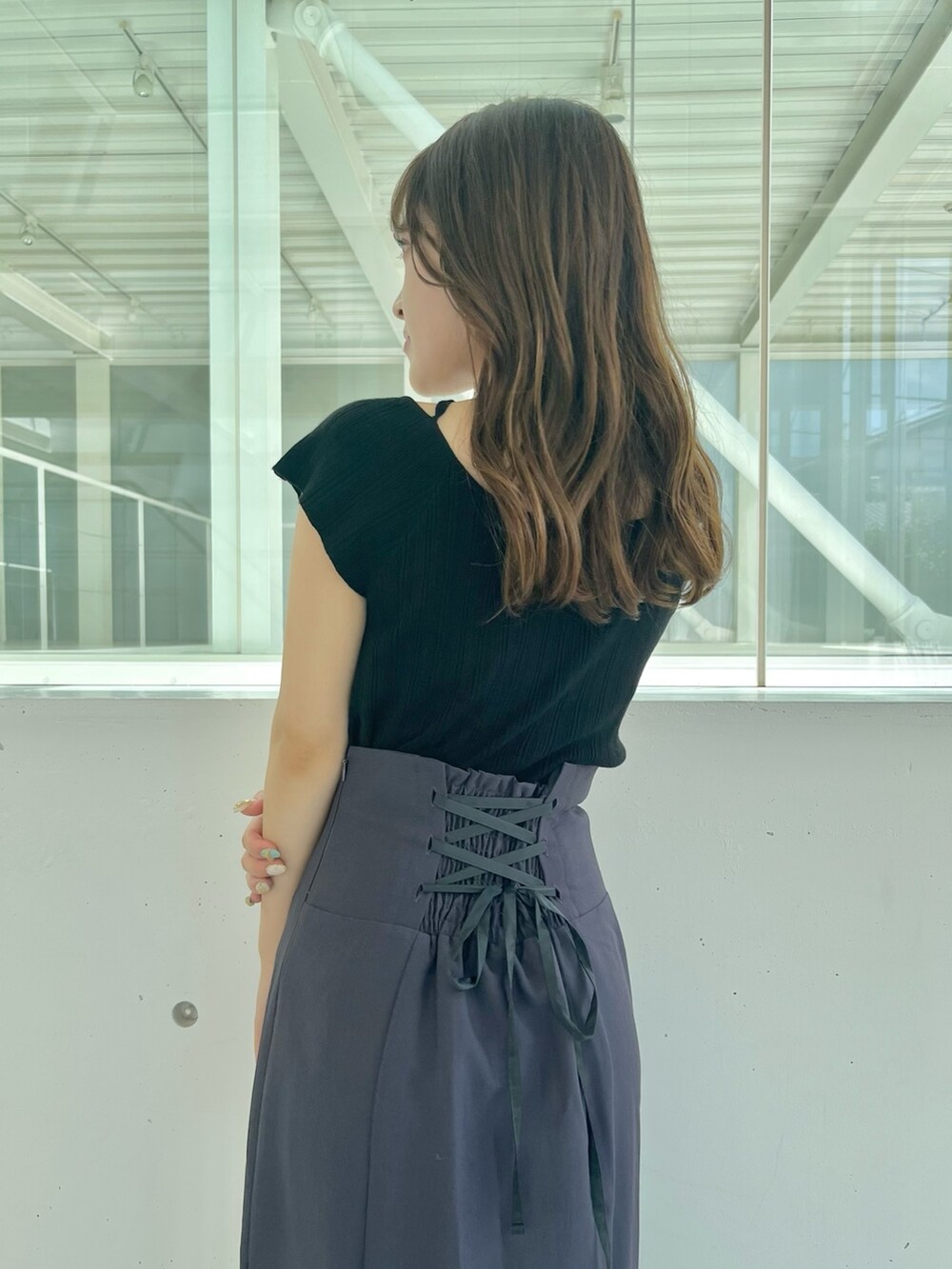 ブラック系のニット/セーター、グレー系のスカート、ブラック系のサンダルを着用したレディースの夏コーディネートの5枚目の写真