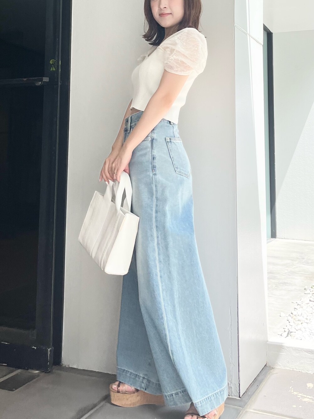 ホワイト系のニット/セーター、ブルー系のデニムパンツ、ホワイト系のトートバッグを着用したレディースの夏コーディネートの6枚目の写真
