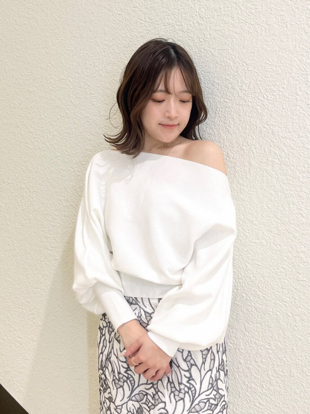 イエロー系のトレンチコート、ホワイト系のニット/セーター、ホワイト系のスカートを着用したレディースの冬コーディネートの6枚目の写真