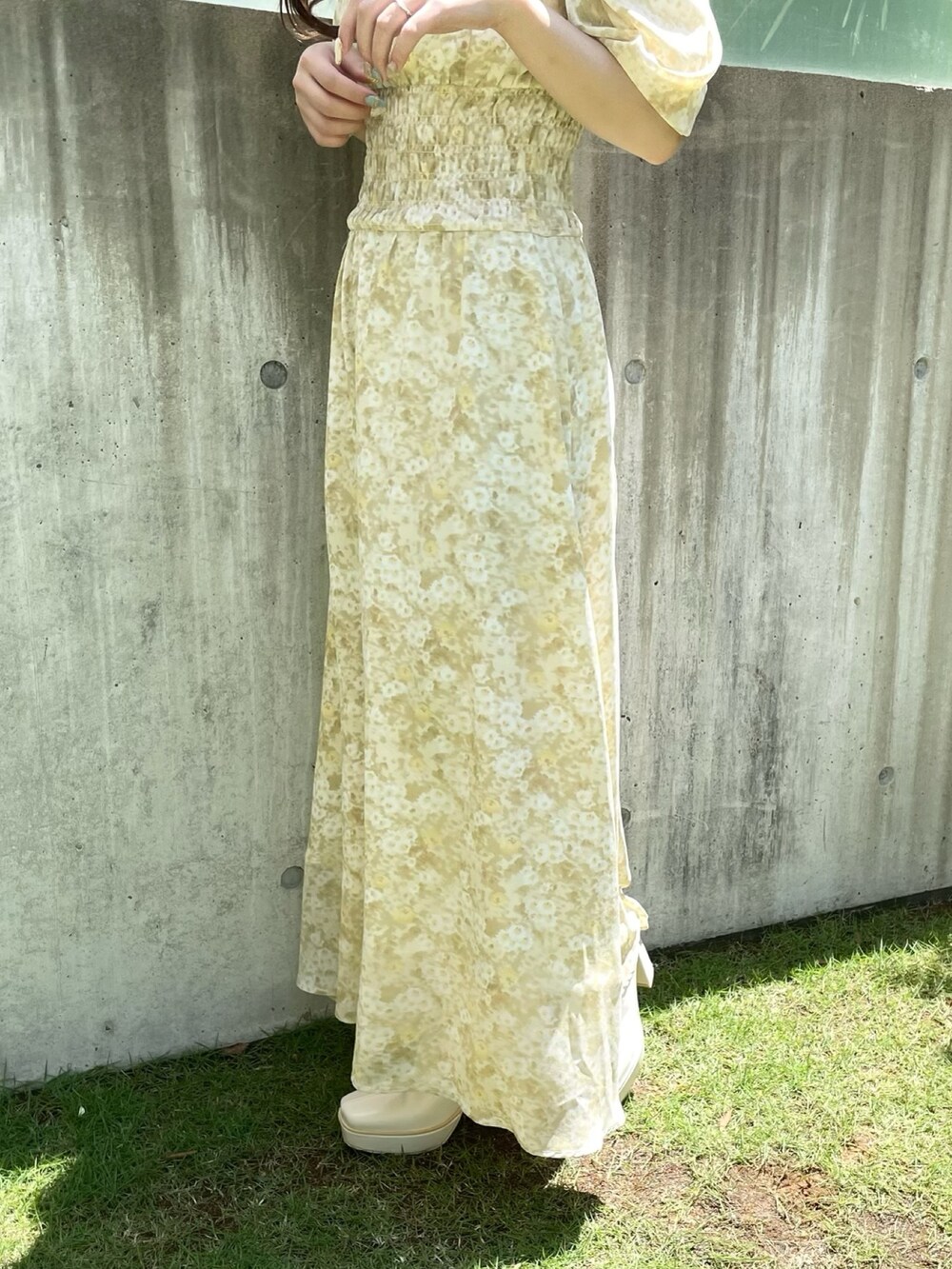 イエロー系のワンピース、ホワイト系のブーツを着用したレディースの夏コーディネートの6枚目の写真