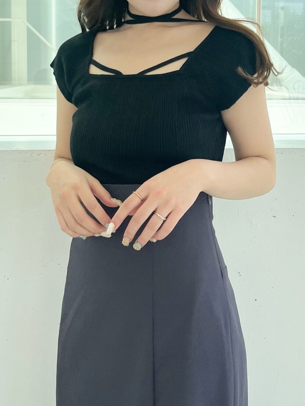 ブラック系のニット/セーター、グレー系のスカート、ブラック系のサンダルを着用したレディースの夏コーディネートの6枚目の写真