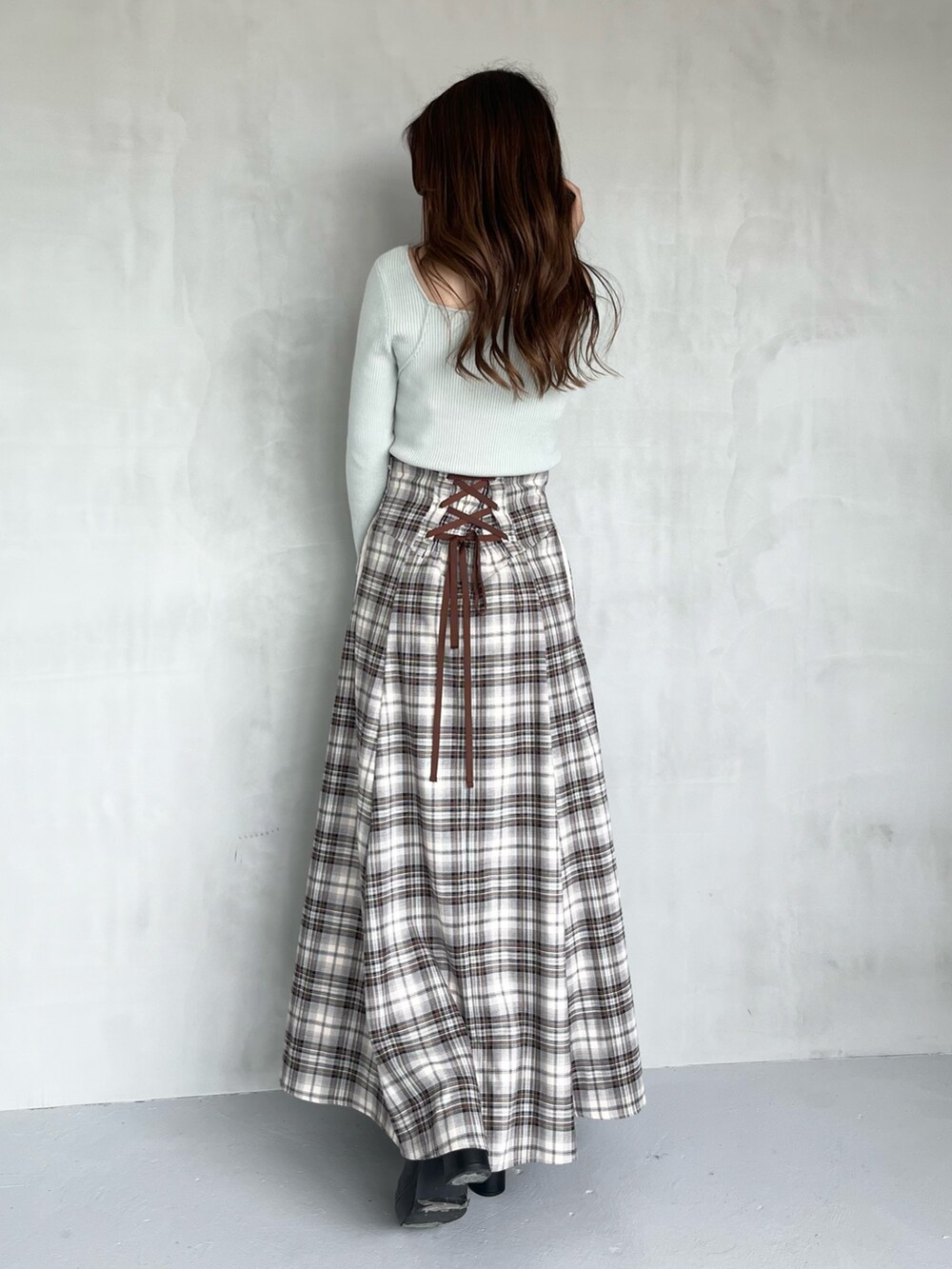 ブラウン系のスカート、グリーン系のニット/セーター、ブラック系のブーツを着用したレディースの秋コーディネートの3枚目の写真