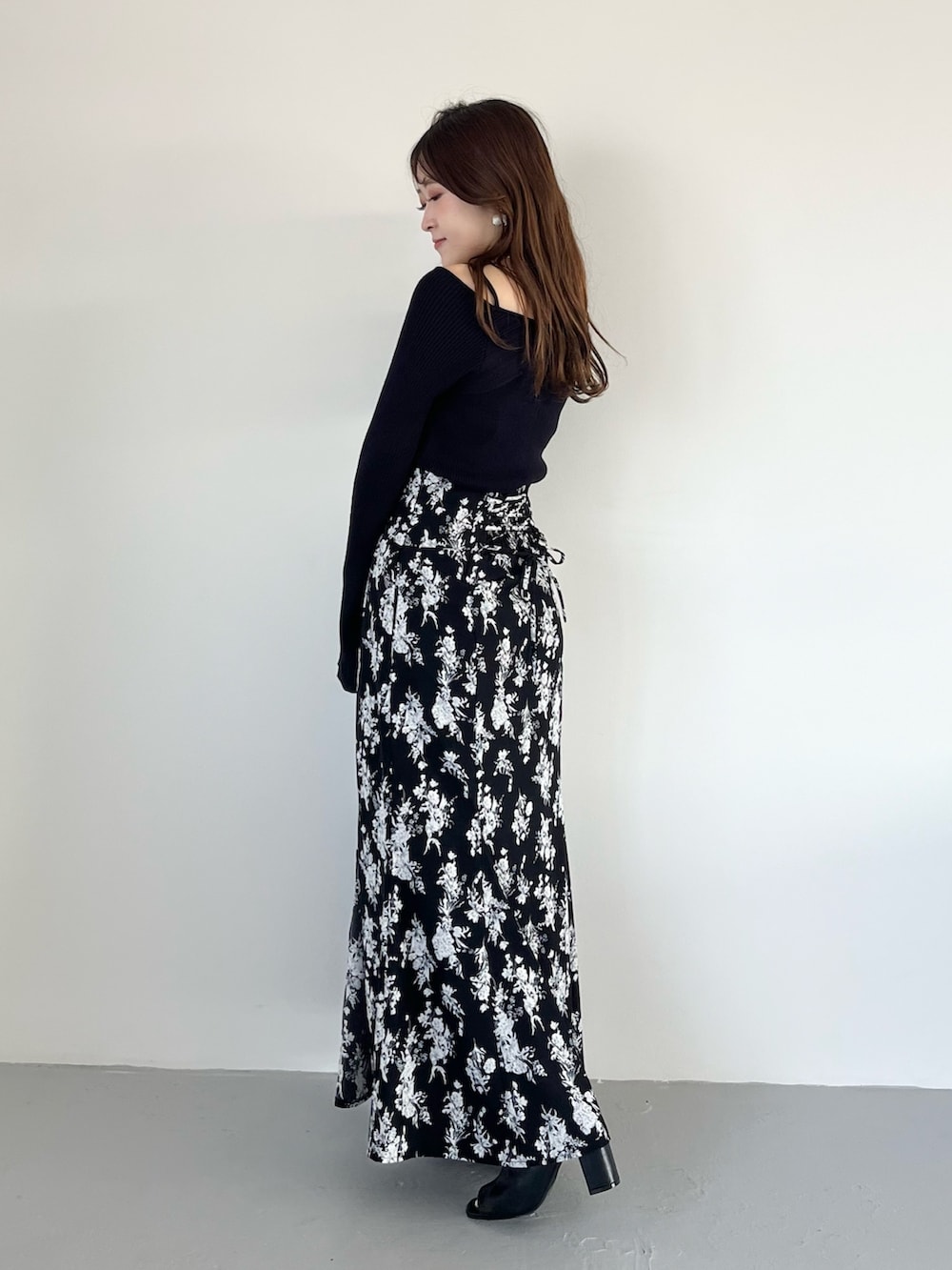 ブラック系のスカート、ブルー系のニット/セーター、ブラック系のブーツを着用したレディースの春コーディネートの2枚目の写真