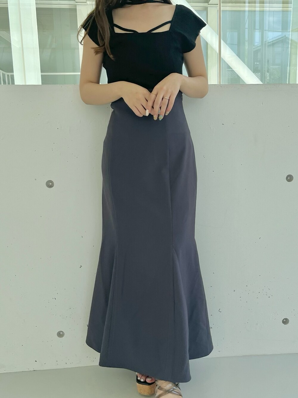 ブラック系のニット/セーター、グレー系のスカート、ブラック系のサンダルを着用したレディースの夏コーディネートの4枚目の写真