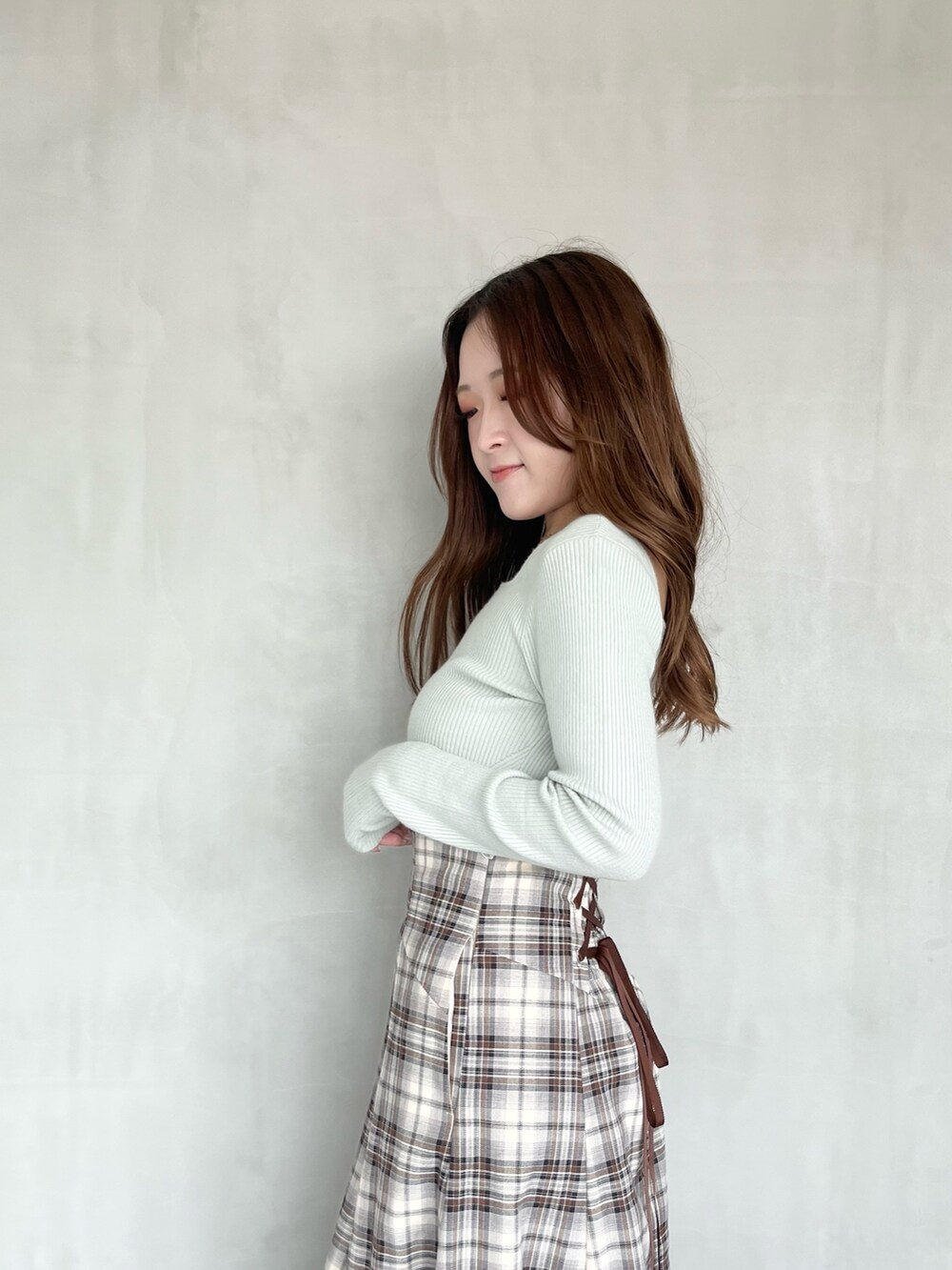 ブラウン系のスカート、グリーン系のニット/セーター、ブラック系のブーツを着用したレディースの秋コーディネートの5枚目の写真