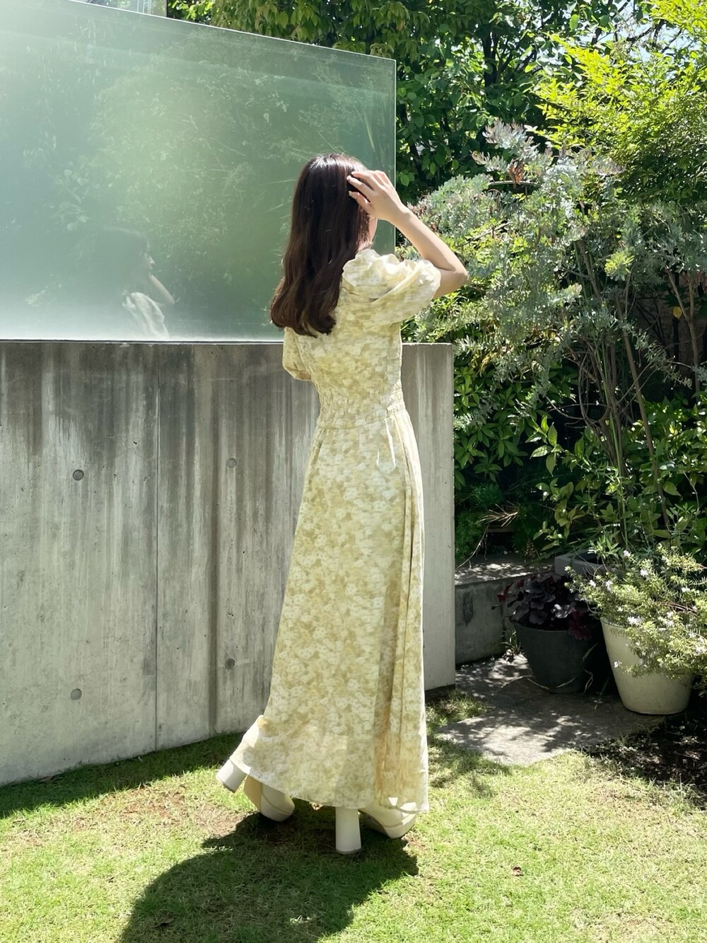 イエロー系のワンピース、ホワイト系のブーツを着用したレディースの夏コーディネートの3枚目の写真