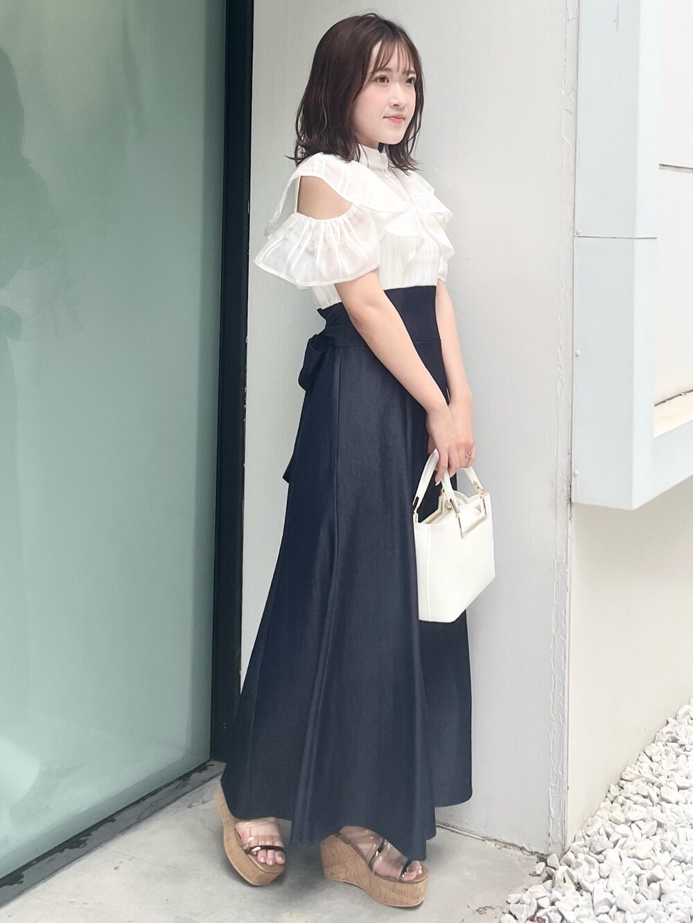 ホワイト系のワンピース、ホワイト系のハンドバッグ、ブラウン系のサンダルを着用したレディースの夏コーディネートの3枚目の写真