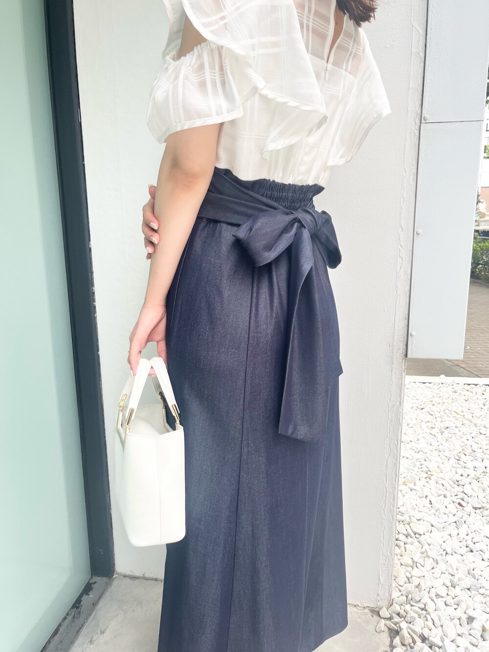 ホワイト系のワンピース、ホワイト系のハンドバッグ、ブラウン系のサンダルを着用したレディースの夏コーディネートの4枚目の写真