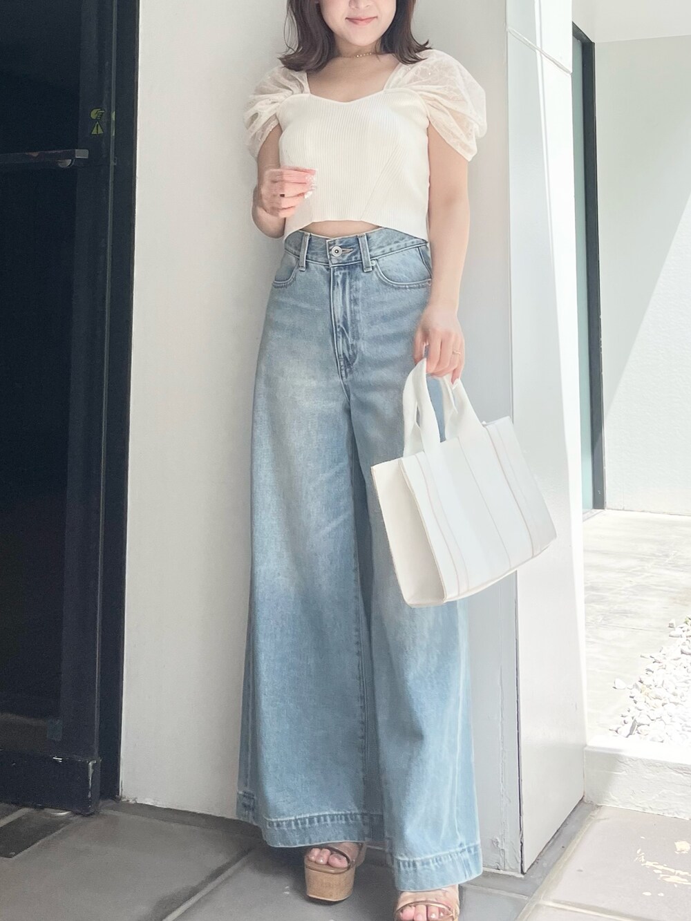 ホワイト系のニット/セーター、ブルー系のデニムパンツ、ホワイト系のトートバッグを着用したレディースの夏コーディネートの5枚目の写真