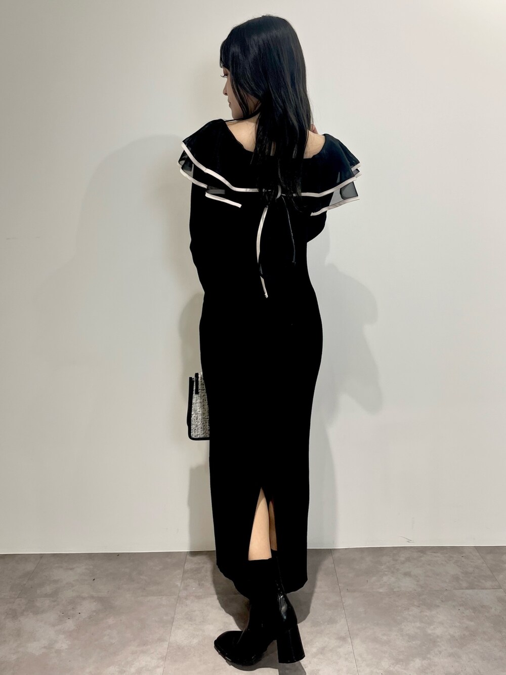 ブラック系のワンピース、ブラック系のショルダーバッグ、ブラック系のブーツを着用したレディースの冬コーディネートの3枚目の写真