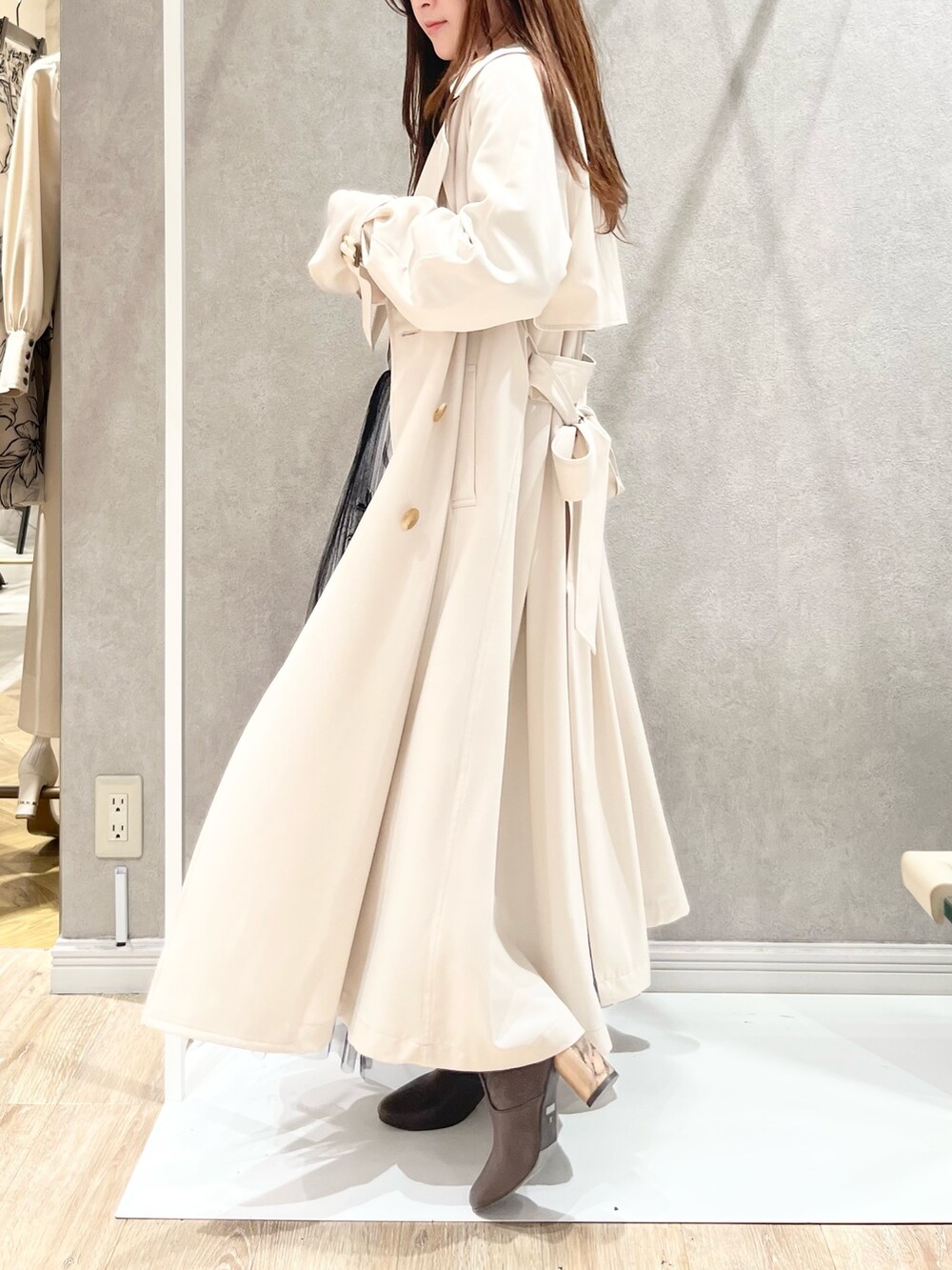 ホワイト系のトレンチコート、ブラック系のスカート、ブラック系のニット/セーターを着用したレディースの冬コーディネートの7枚目の写真