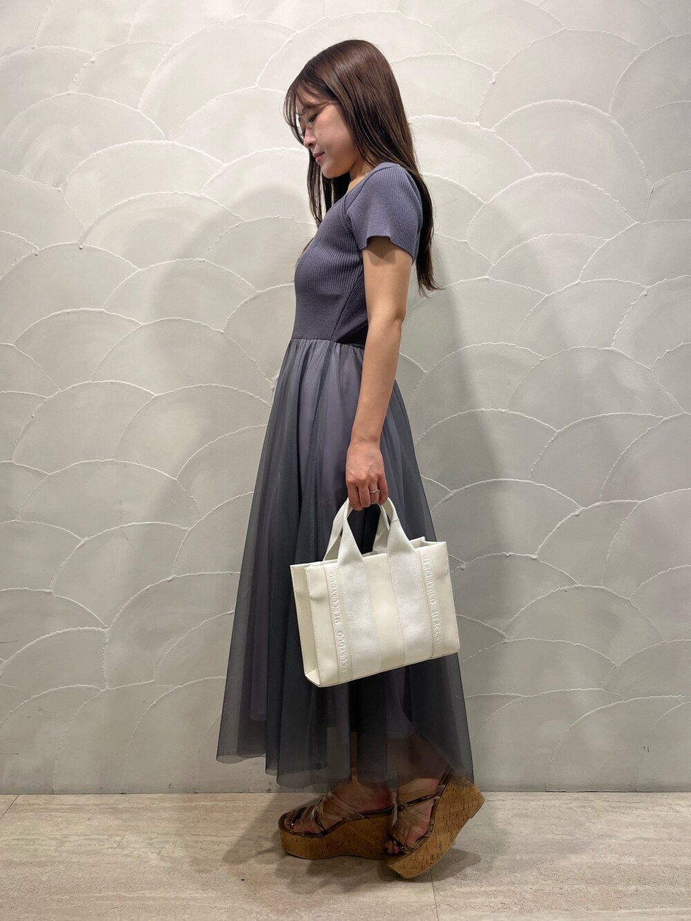 グレー系のワンピース、ホワイト系のトートバッグ、ホワイト系のカーディガン/ボレロを着用したレディースの春コーディネートの3枚目の写真