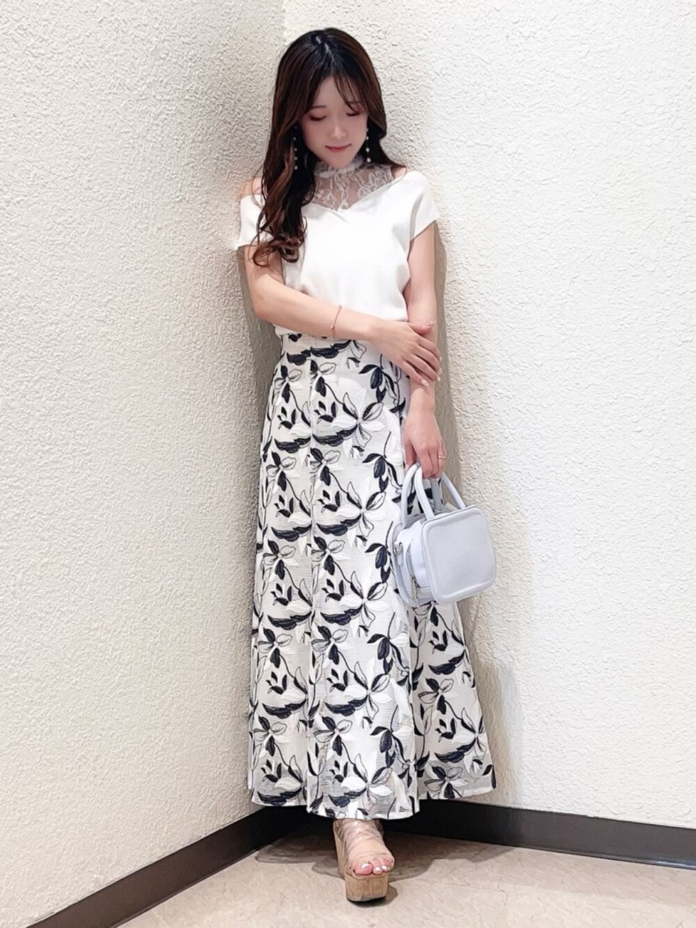 ホワイト系のニット/セーター、ホワイト系のスカート、その他のサンダルを着用したレディースの春コーディネートの2枚目の写真