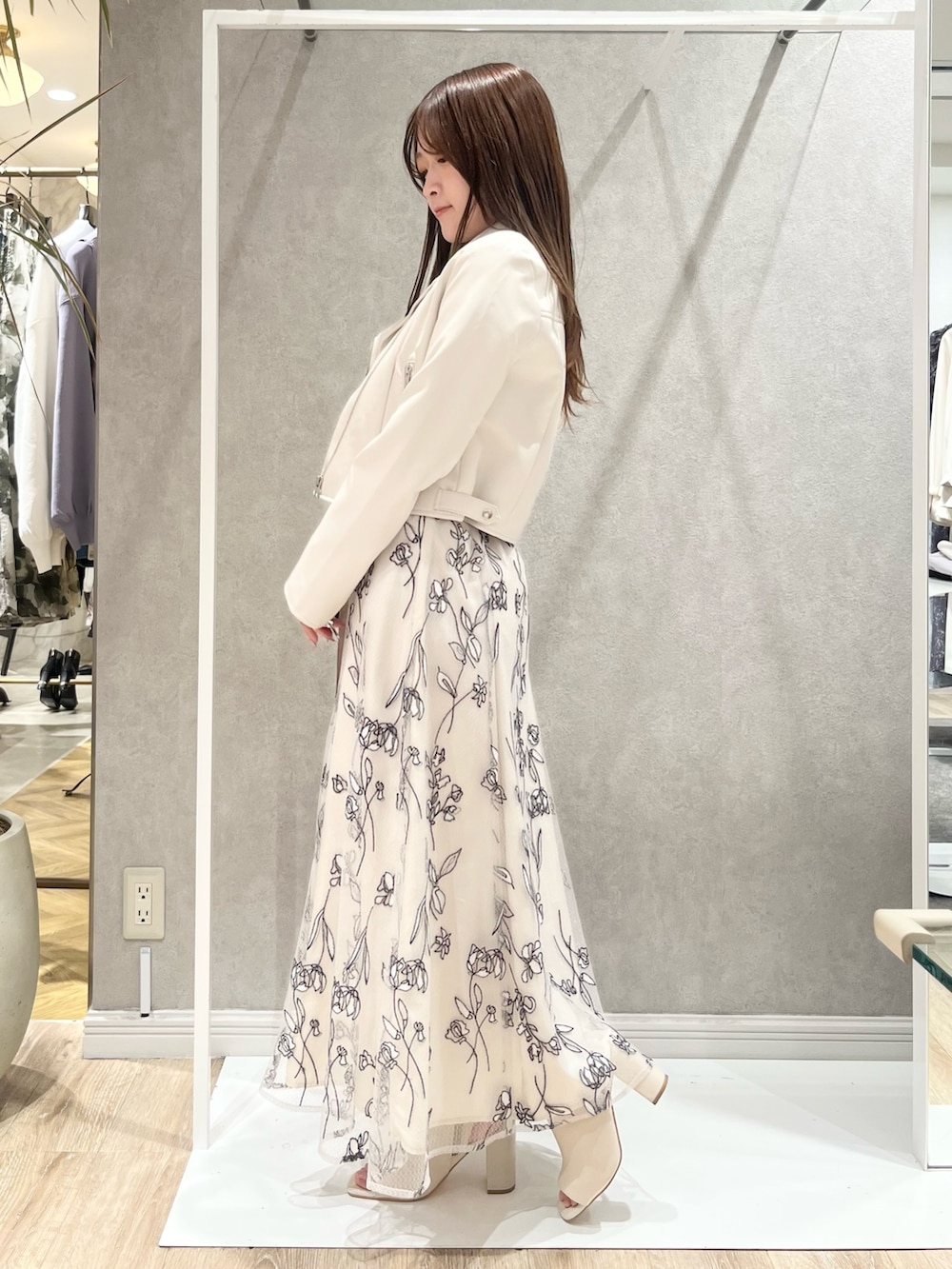 ベージュ系のワンピース、ホワイト系のライダースジャケット、ホワイト系のブーツを着用したレディースの春コーディネートの2枚目の写真