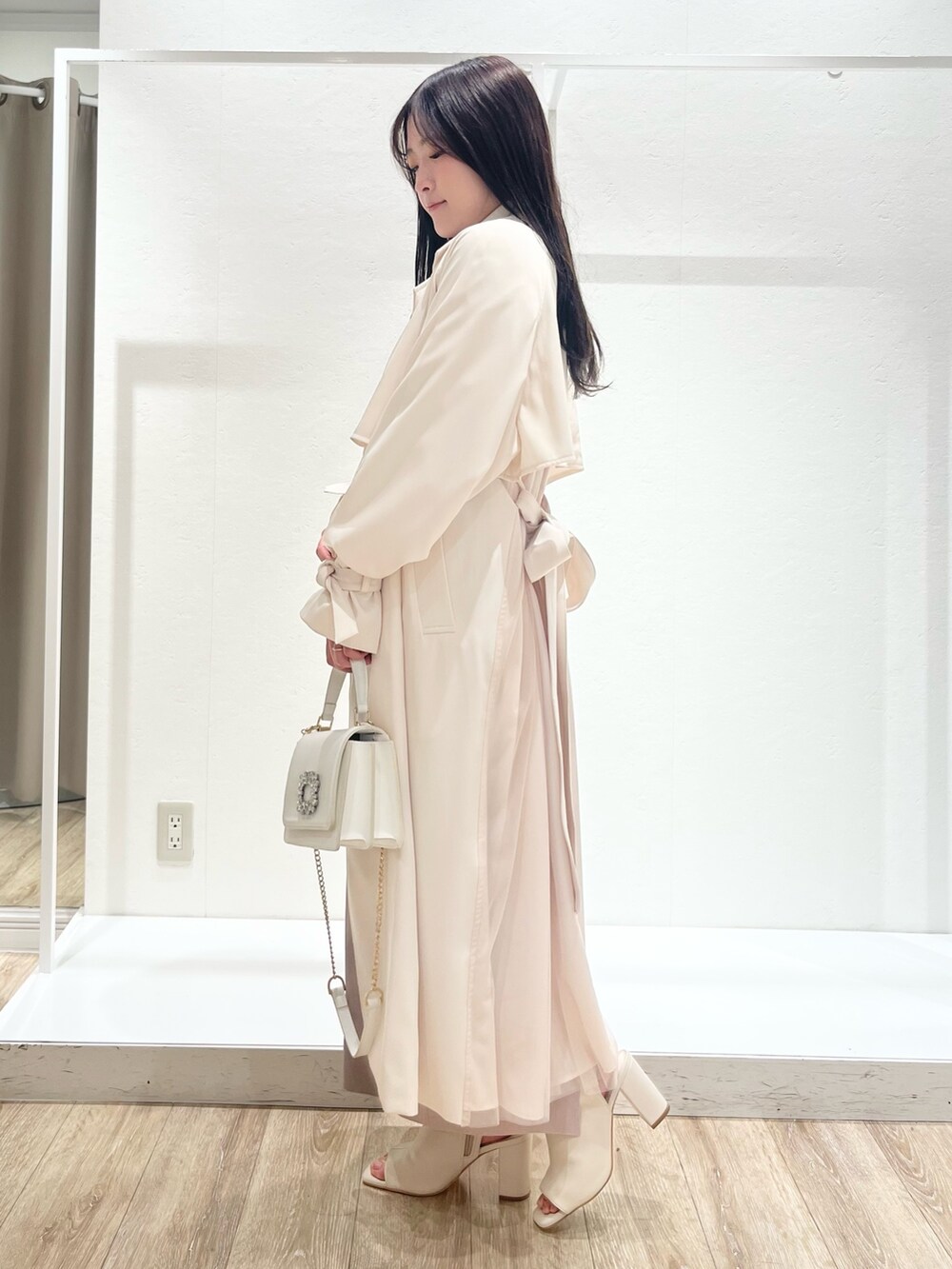 ホワイト系のトレンチコート、ベージュ系のワンピース、ホワイト系のショルダーバッグを着用したレディースの春コーディネートの2枚目の写真