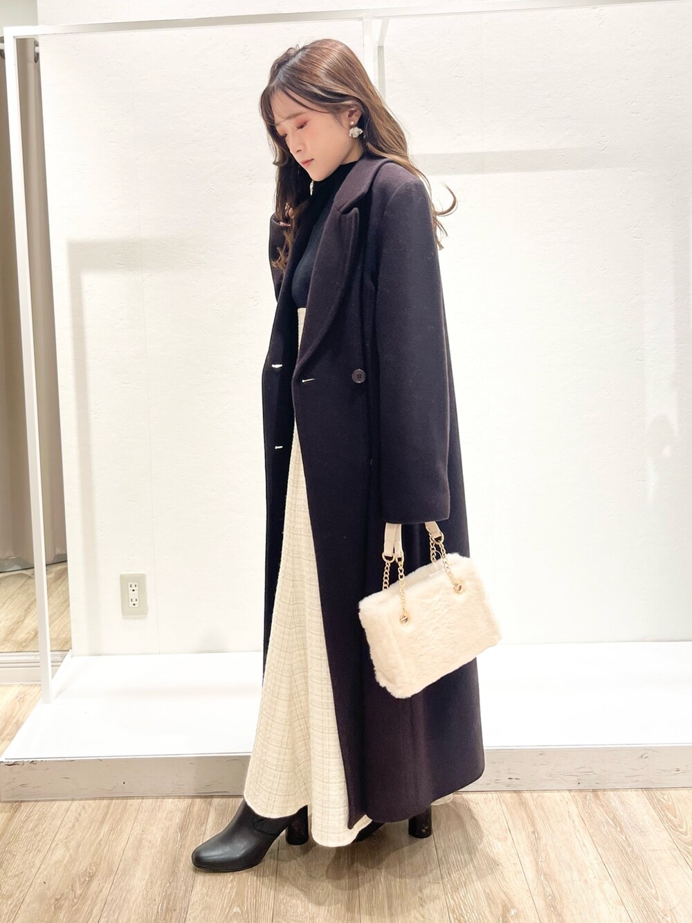 ホワイト系のワンピース、ブラウン系のチェスターコート、ホワイト系のハンドバッグを着用したレディースの秋コーディネートの2枚目の写真