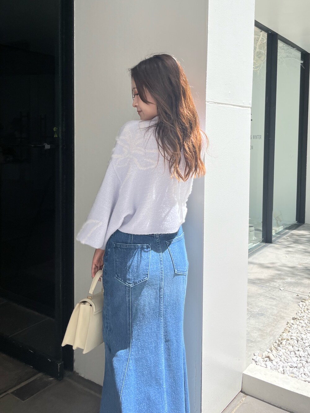 ブルー系のニット/セーター、ブルー系のデニムスカート、ベージュ系のブーツを着用したレディースの秋コーディネートの5枚目の写真