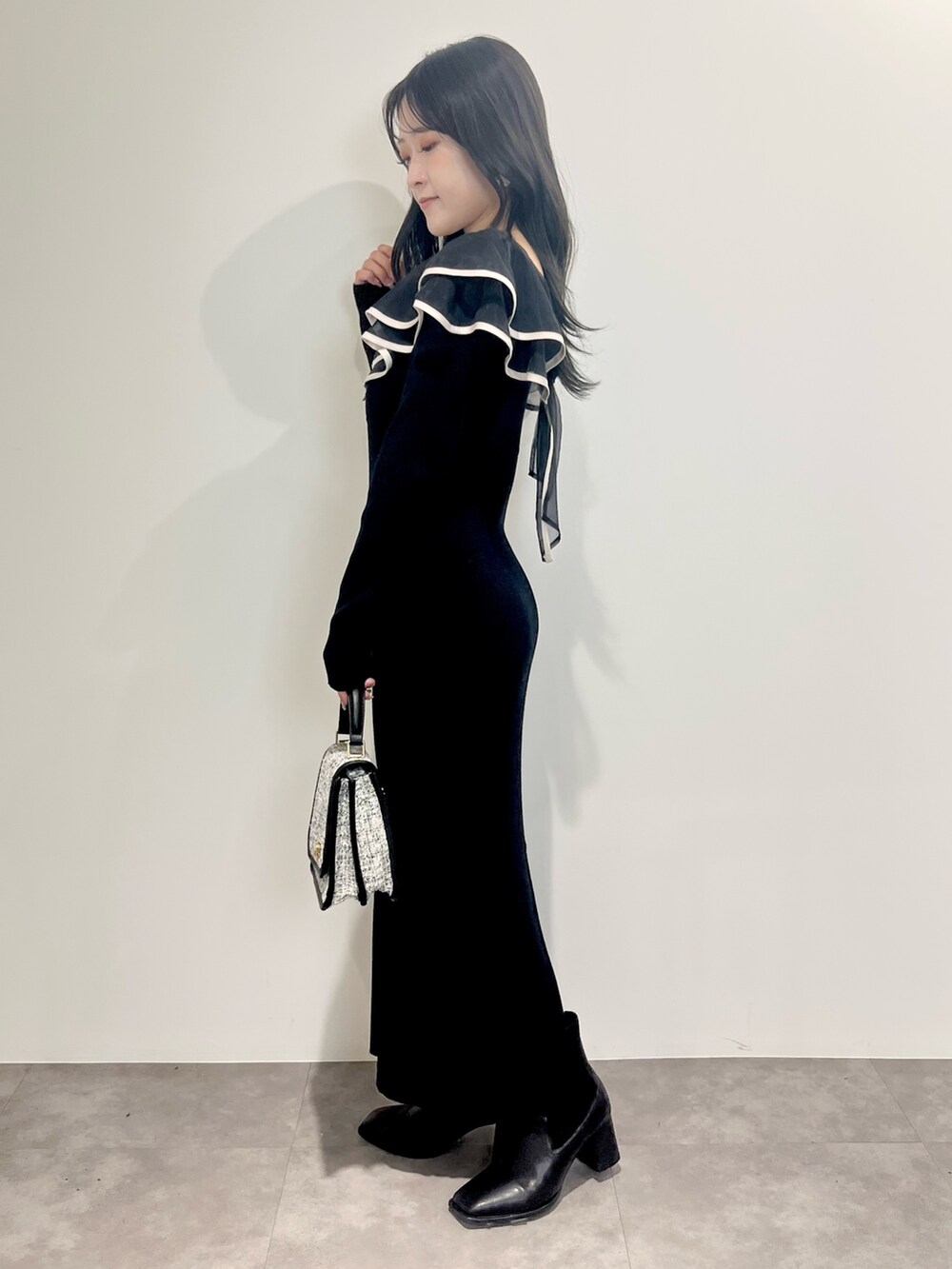 ブラック系のワンピース、ブラック系のショルダーバッグ、ブラック系のブーツを着用したレディースの冬コーディネートの2枚目の写真