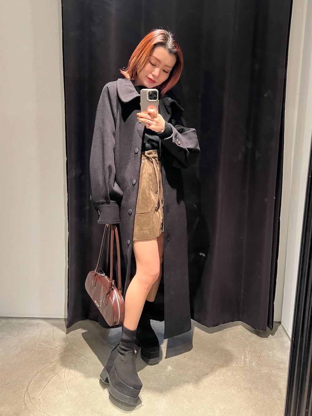 ブラック系のブーツ、ブラウン系のスカート、ブラック系のニット/セーターを着用したレディースの冬コーディネートの2枚目の写真