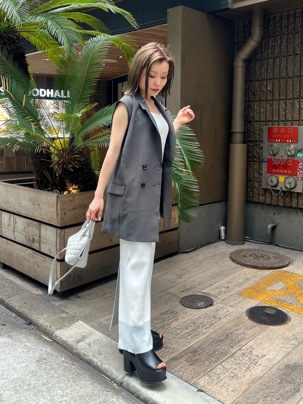 ホワイト系のワンピース、グレー系のベスト、ブラック系のサンダルを着用したレディースの春コーディネートの3枚目の写真