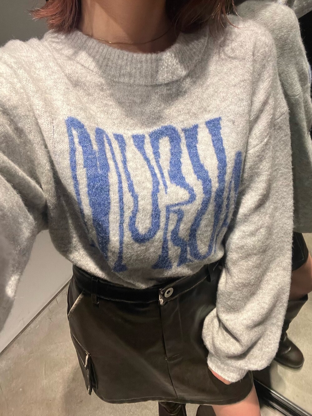 グレー系のニット/セーター、ブラウン系のブーツ、ブラウン系のスカートを着用したレディースの冬コーディネートの6枚目の写真