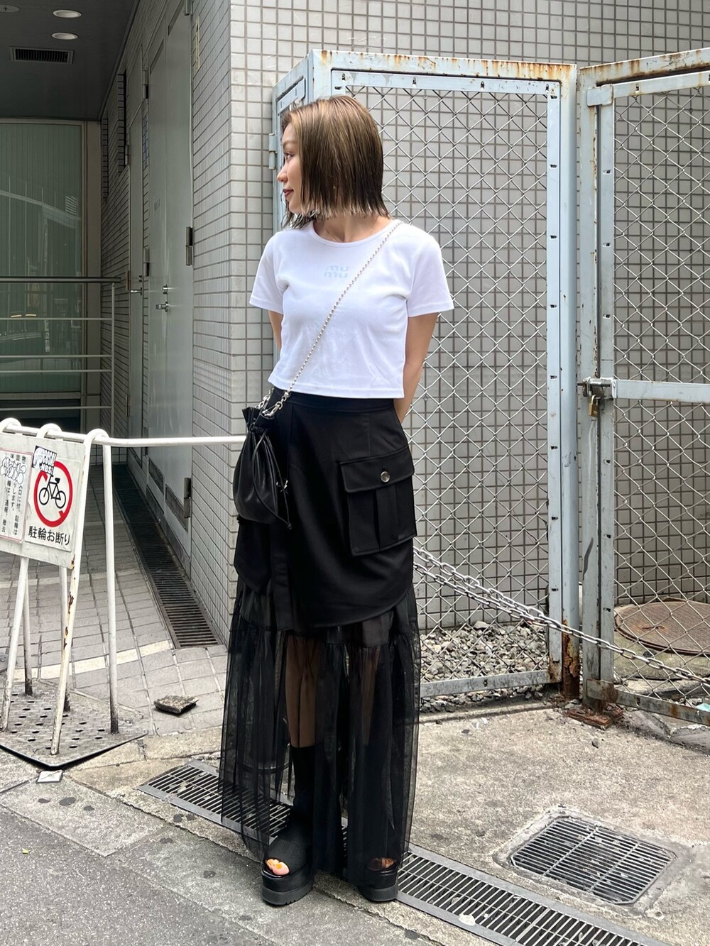 ホワイト系のTシャツ/カットソー、ブラック系のスカート、ブラック系のショルダーバッグを着用したレディースの春コーディネートの2枚目の写真